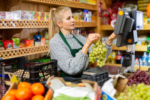Portrait of a positive female salesperson at the checkout counter at a grocery supermarket