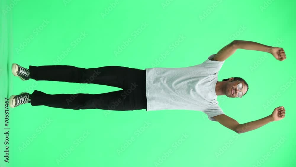 A man in a gray T-shirt, on a green background, full-length, jumps