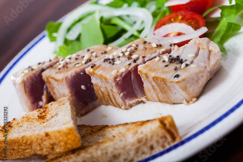 Seafood. Seared tuna steaks sprinkled with sesame with garnish of fresh greens and grilled bread slices