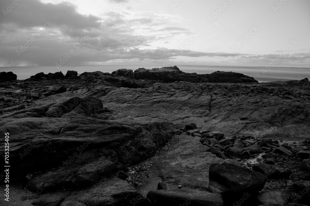 Black and white seascape of Morecambe Bay with dramatic atmospheric clouds casting shadows, capturing the tranquil beauty of the coastal scenery. Black and white seascape of Morecambe Bay with dramatic atmospheric clouds casting shadows, capturing the tranquil beauty of the coastal scenery.