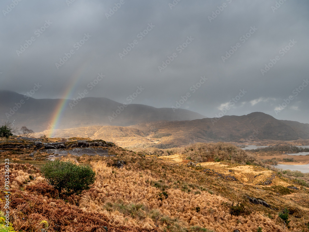 Rainbow over magnificent nature scene with valley in a mountains and dark dramatic sky. Ladies view, Killarney, Ireland, ring of Kerry route. Magnificent Irish nature and popular tourist area.