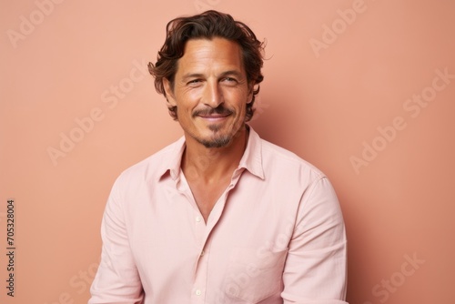 Handsome middle-aged man in a pink shirt on a pink background © Inigo