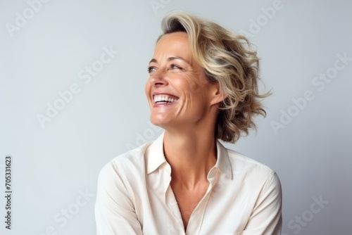 Portrait of a beautiful mature businesswoman laughing against a grey background photo