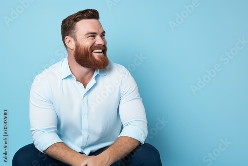 Portrait of a happy bearded man sitting on a blue background.