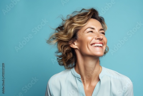 Portrait of happy smiling middle aged woman with curly hair over blue background photo