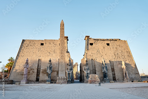 Seated statue of Ramesses II by the First pylon of the Luxor Temple, Egypt. Columns and statues of the Luxor temple main entrance, first pylon, Egypt