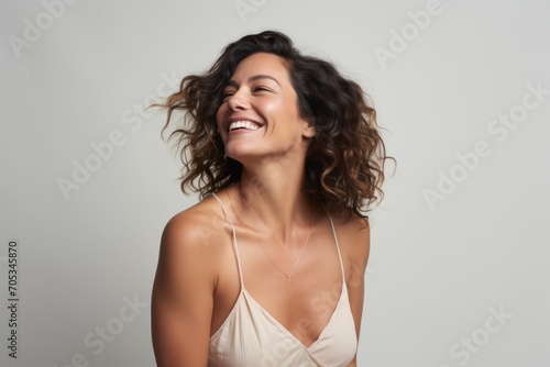 Portrait of a beautiful young woman laughing isolated on grey background.
