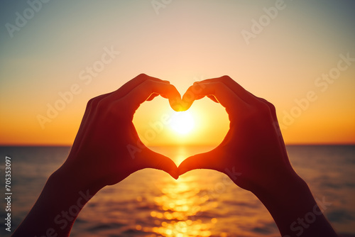 Hands Forming a Heart Shape Against Ocean Sunset