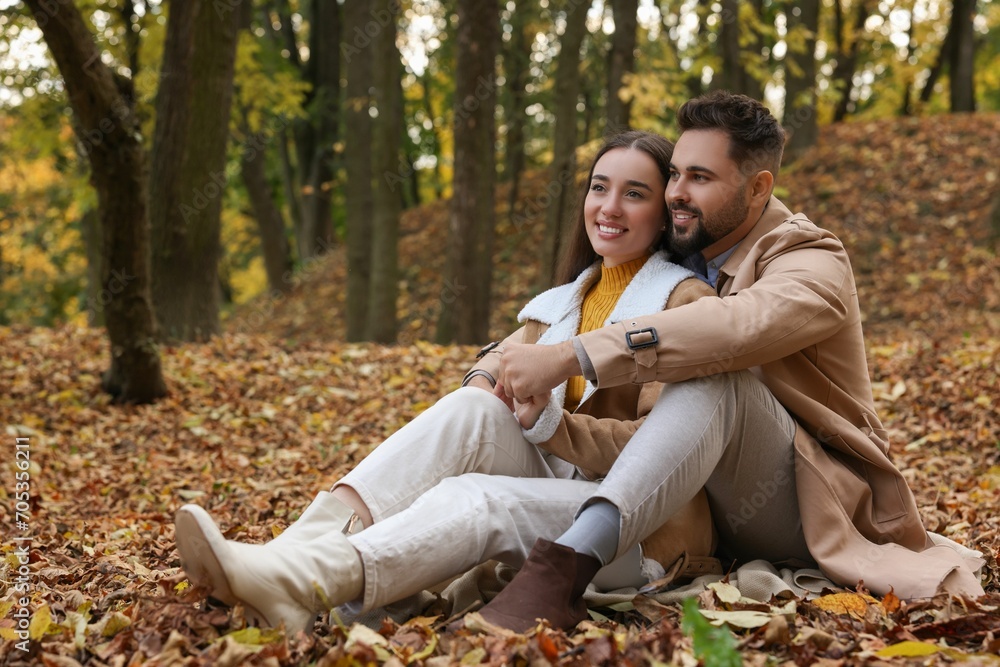 Fototapeta premium Romantic young couple spending time together in autumn park, space for text