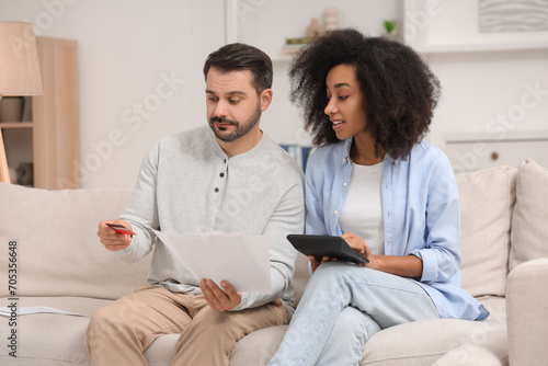 Confused couple with debt notifications, calculator and credit card planning budget at home. Financial problem