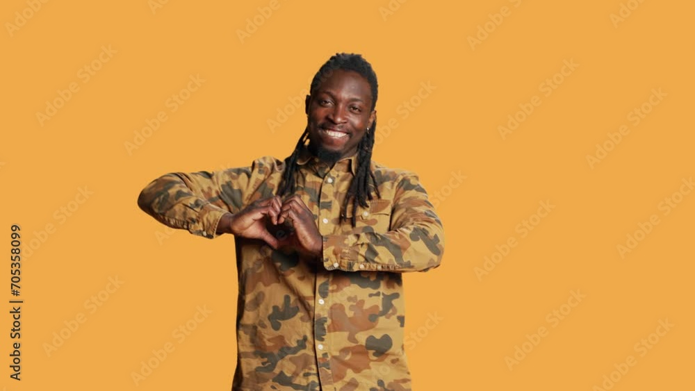Male model presenting heart shape sign in studio, creating romantic flirty gesture to show his sincere emotions and feelings. Young adult doing love symbol on camera, romance concept. Male model presenting heart shape sign in studio, creating romantic flirty gesture to show his sincere emotions and feelings. Young adult doing love symbol on camera, romance concept.