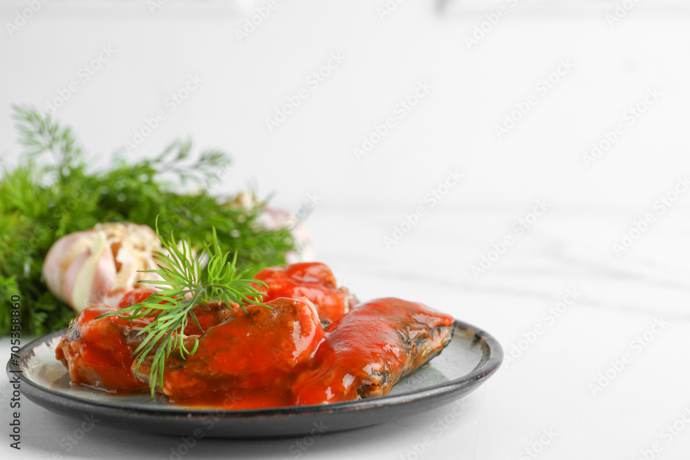 Plate with canned fish in tomato sauce and dill on white table Plate with canned fish in tomato sauce and dill on white table