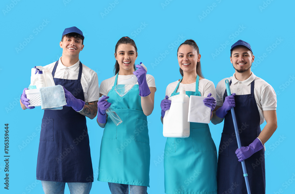 Young janitors with cleaning supplies on blue background Young janitors with cleaning supplies on blue background