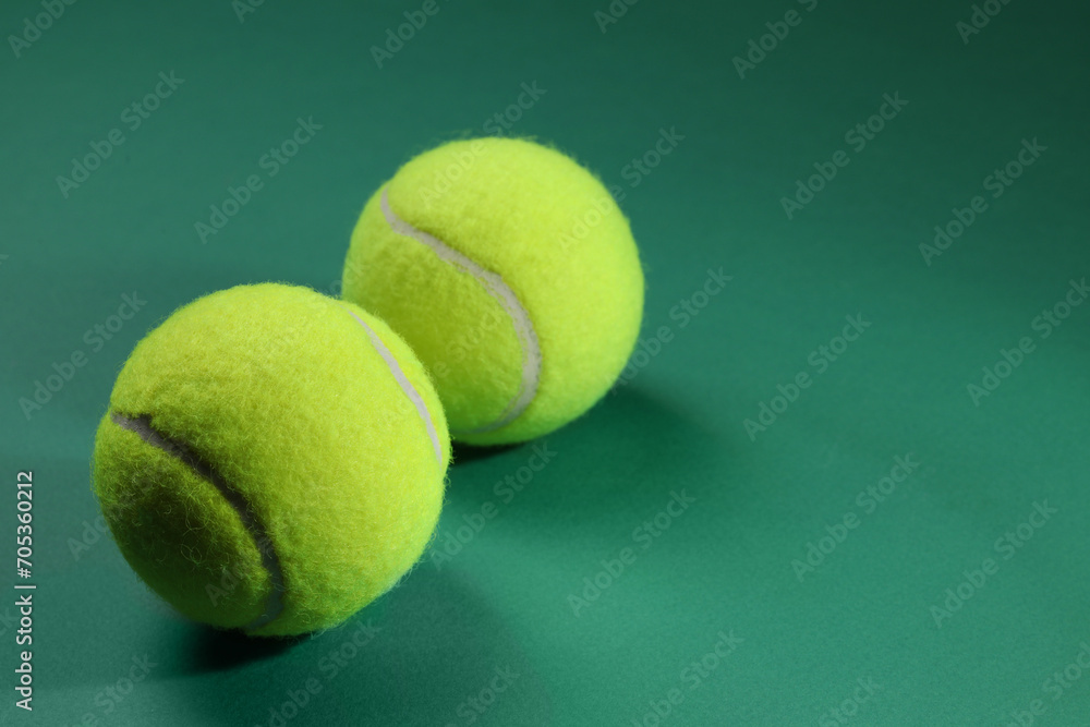 Two tennis balls on green background, space for text