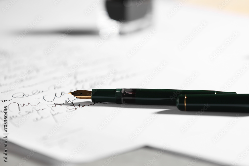 Fototapeta premium Elegant fountain pen and handwritten letter on table, closeup