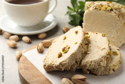 Tasty halva with pistachios served on grey table, closeup