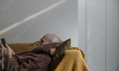 Adult man lying on sofa looking at mobile phone
