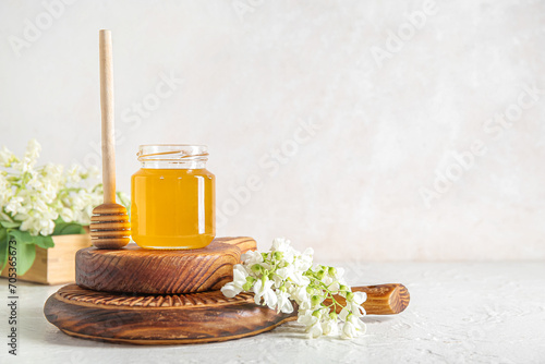 Fototapeta Naklejka Na Ścianę i Meble -  Jar of honey with flowers of acacia and dipper on light background