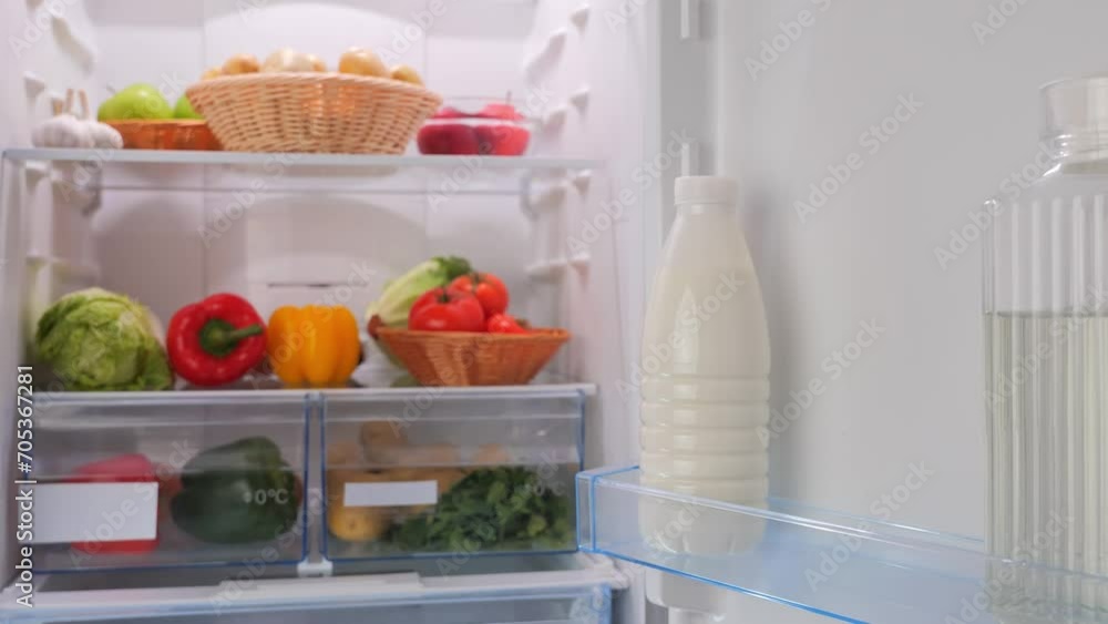 male hands take a bottle of cherry juice from the fridge with vegetables male hands take a bottle of cherry juice from the fridge with vegetables
