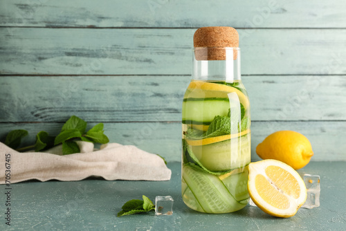 Bottle of lemonade with cucumber and mint on blue table