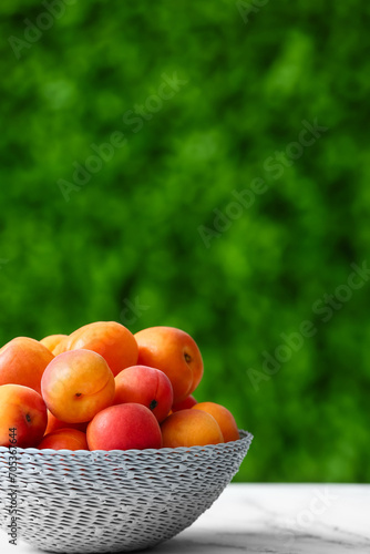Fototapeta Naklejka Na Ścianę i Meble -  Wicker bowl with fresh apricots on white table outdoors