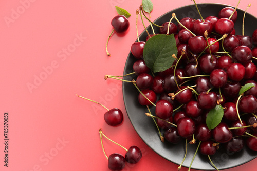 Plate with sweet cherries on red background photo