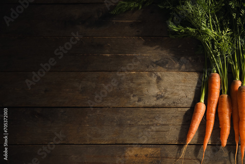 Fresh carrots with leaves on wooden background photo