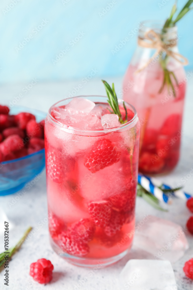 Glass and bottle of fresh raspberry lemonade with rosemary on white table Glass and bottle of fresh raspberry lemonade with rosemary on white table