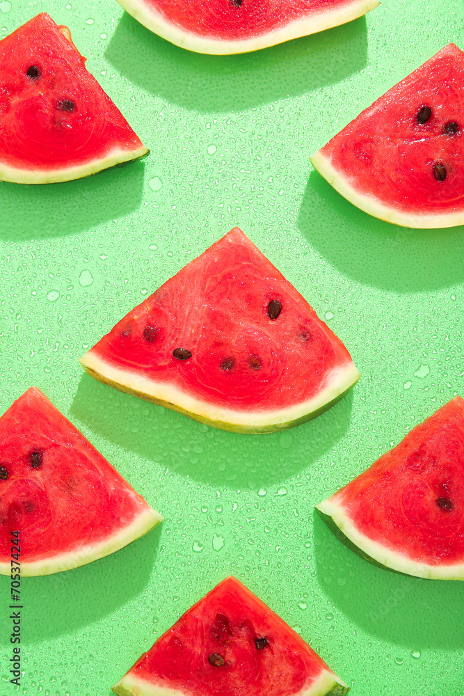 Composition with pieces of fresh ripe watermelon and water drops on green background Composition with pieces of fresh ripe watermelon and water drops on green background
