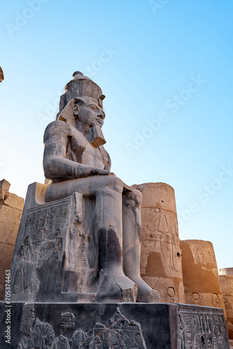 Seated statue of Ramesses II by the First pylon of the Luxor Temple, Egypt. Columns and statues of the Luxor temple main entrance, first pylon, Egypt photo