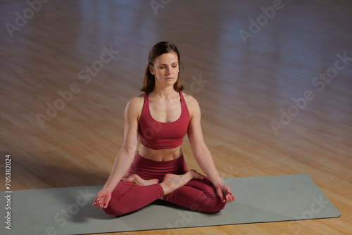 athletic girl doing yoga asana in a studio with large windows