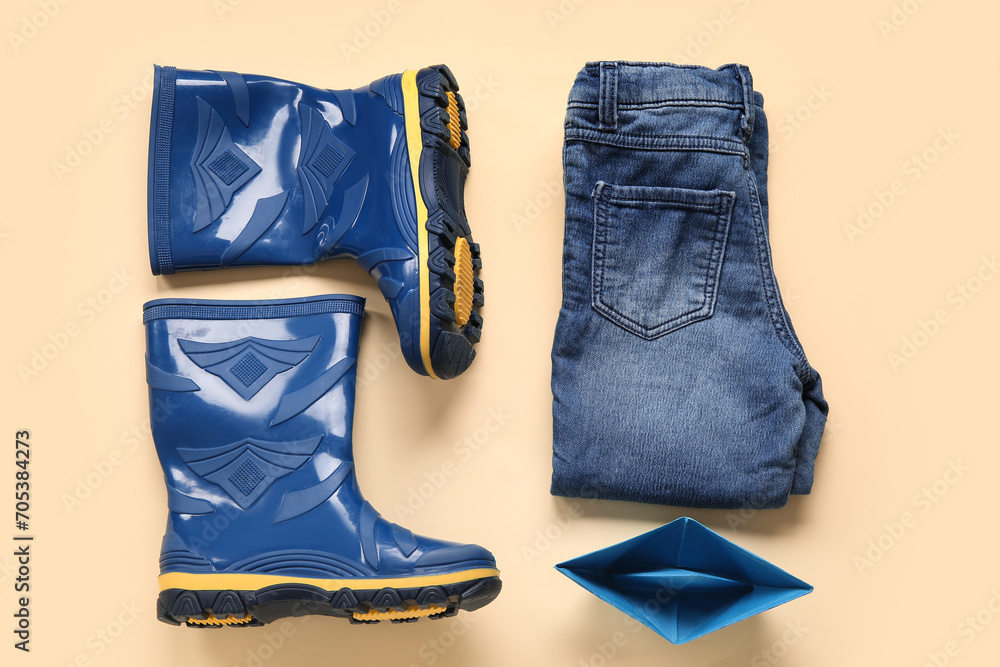 Blue gumboots with jeans and paper ship on yellow background Blue gumboots with jeans and paper ship on yellow background