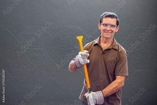 man smiling with gloves and a crowbar in his hands working construction with gloves and safety goggles