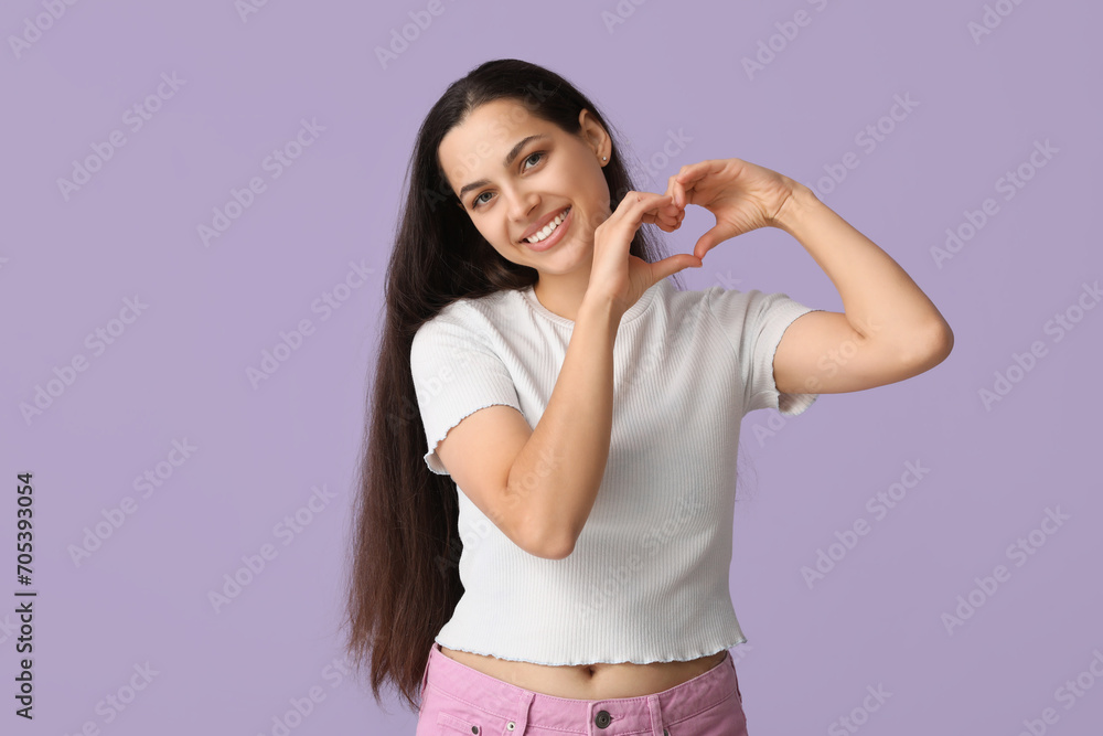 Happy young woman making heart with her hands on lilac background Happy young woman making heart with her hands on lilac background