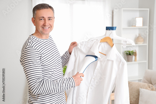 Mature man steaming shirt a...