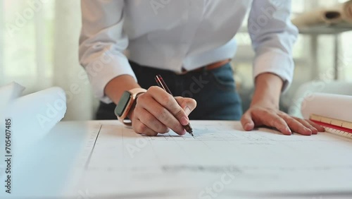 Hand of architect woman inspects detail of building in the construction drawing paper or blueprint on the desk office, Working on architect-designer jobs or Engineer designer concept. photo