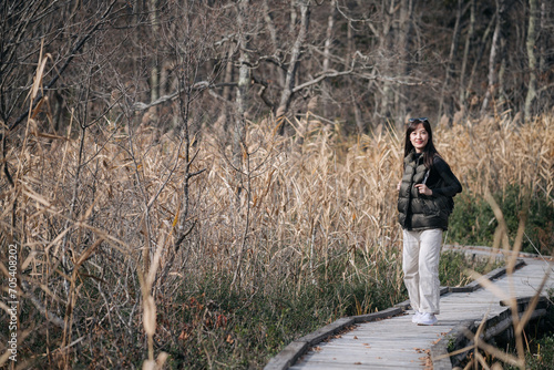 Nature's embrace, Asian traveler, a young Asian woman, revels in a solo hike along a scenic Japanese trail in fall.