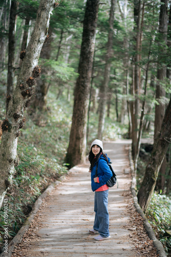 Asian woman s solo trek in Japan s November  Blue jacket  colorful foliage. Behind the scenes happiness and elegance in a portrait of nature s joy.