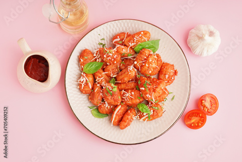 Plate of tasty gnocchi with cheese on pink background
