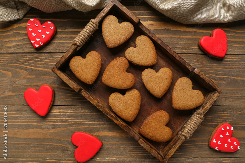 Fototapeta premium Tray with tasty heart shaped cookies and tablecloth on wooden background. Valentine's Day celebration