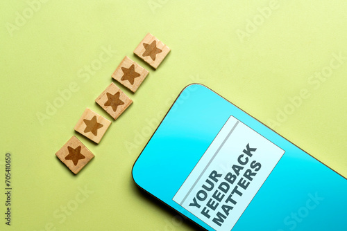 Word Your Feedback Matters on the mobile phone screen and a wooden cube five star rating