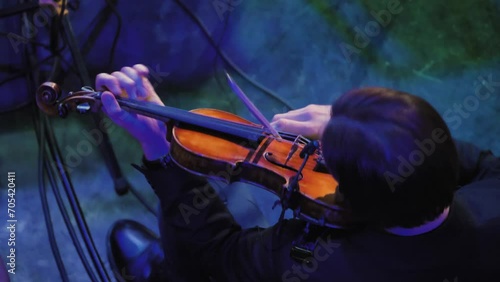 Close-up of a man combining violin playing techniques. First he plays pizzicato and then he plays with a bow. View from above from behind. Violinist with a symphony orchestra