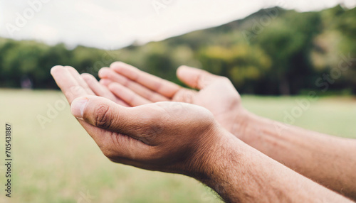 Hands in prayer, open in respect, against serene nature backdrop © Your Hand Please
