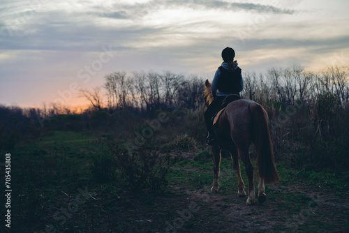 young Latin woman riding her horse in the Argentinean countryside at sunset