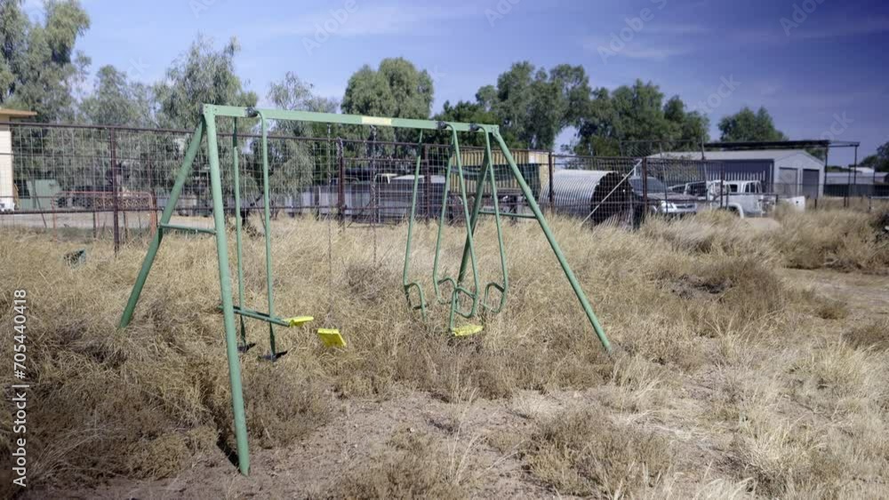 Abandoned swing set in overgrown rural dry grass Abandoned swing set in overgrown rural dry grass