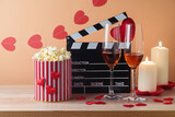Happy Valentine's day and romantic movie concept with  movie clapper board, heart shapes, wine and popcorn on wooden table over trendy background