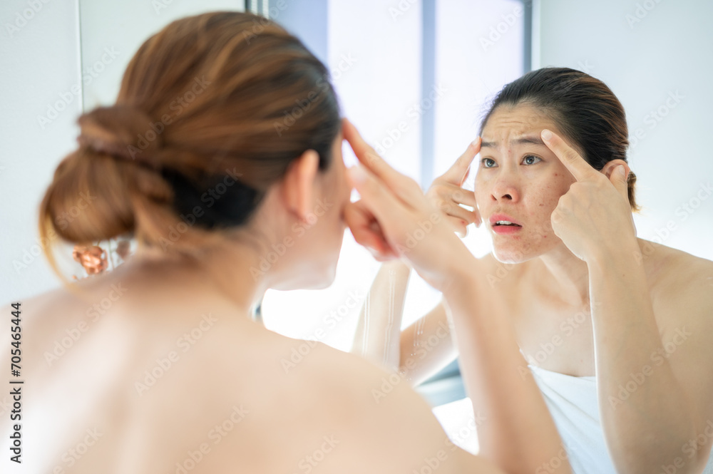 Asian woman having stress after looking her face in mirror. She dissatisfied her face caused of acne and scar problem. Asian woman having stress after looking her face in mirror. She dissatisfied her face caused of acne and scar problem.