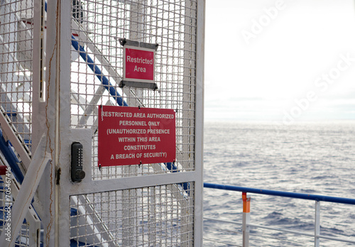 Horizontal Close-Up of Restricted Area Warning Signs on a Ship Metal Gate, Ocean Background, No People, Daytime