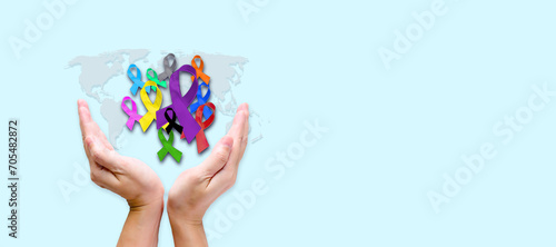 Hand hold many color of ribbons for World cancer awareness day banner and background. colorful awareness ribbons; blue, red, green, pink and a yellow color