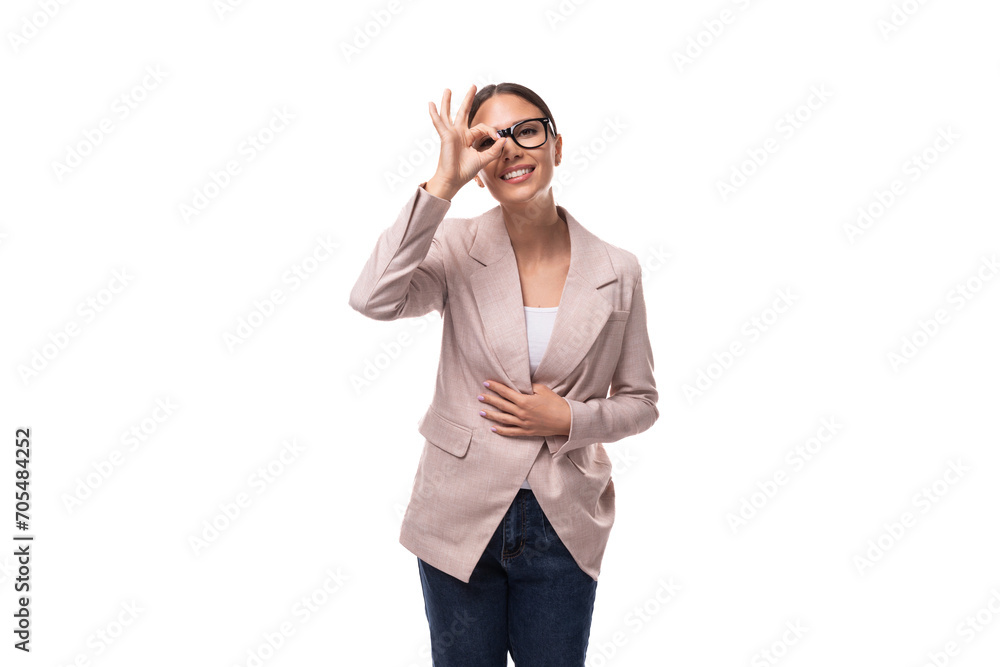 a young positive brunette with her hair gathered in a ponytail, dressed in a light jacket, smiles and makes a face a young positive brunette with her hair gathered in a ponytail, dressed in a light jacket, smiles and makes a face